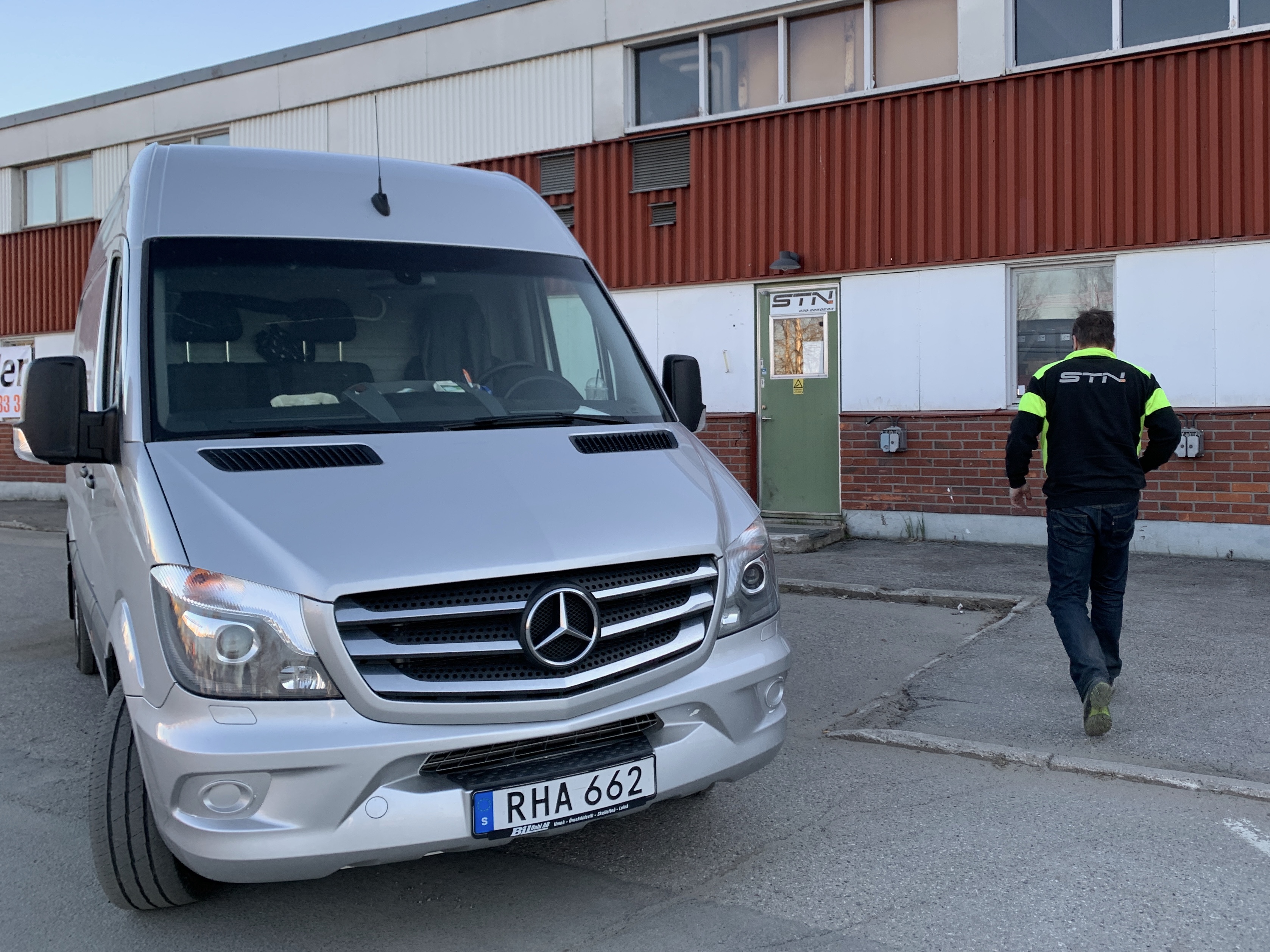 Silvergrå Mercedes Sprinter framför STN:s verkstad i Boden